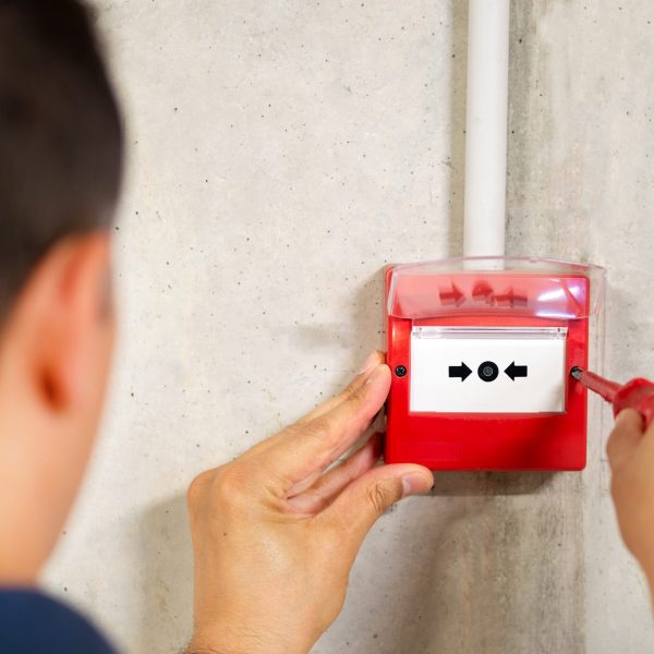 A back view of electrician installing fire alarm system